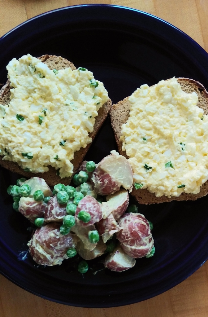 Egg salad sandwich and potato salad with peas